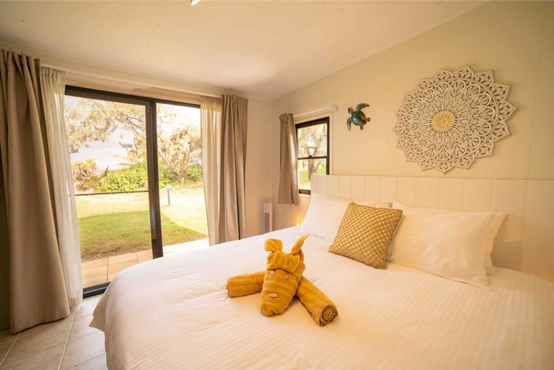 Bright island-style bedroom with a neatly made bed and garden view