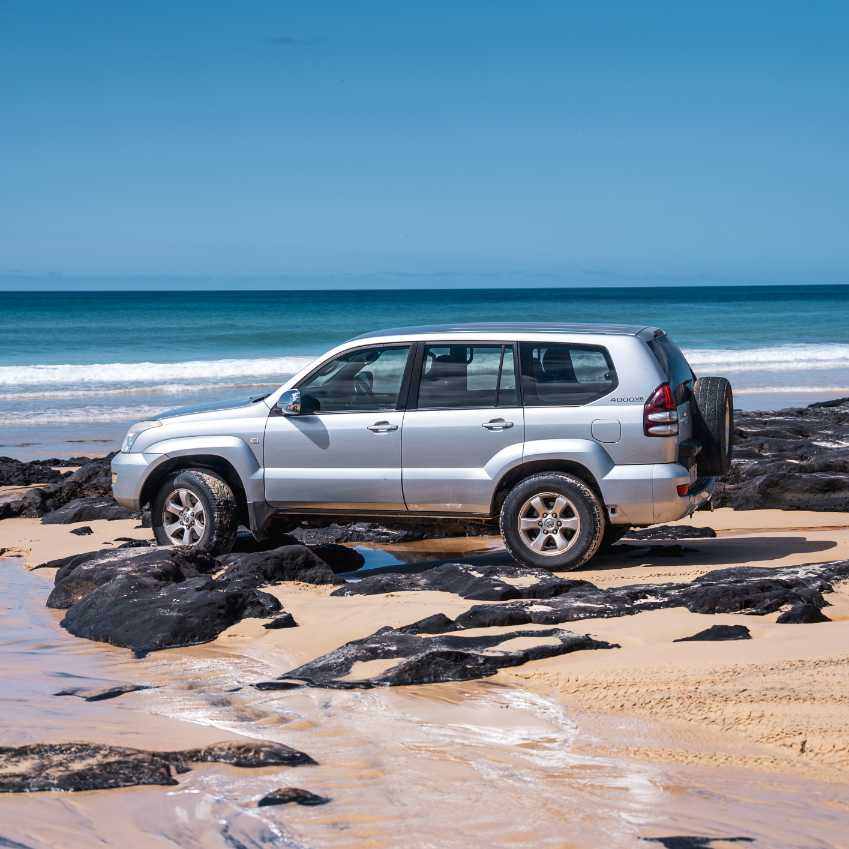 4WD vehicle on sandy beach with ocean backdrop